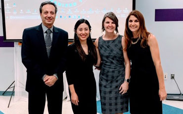 Four people standing together at an Alpha Beta Gamma event