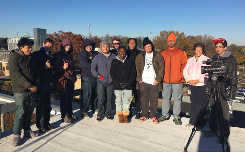 Twelve people on a rooftop gathered for a photo