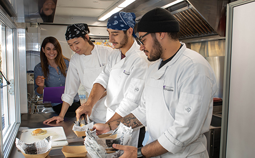 Jana Anderson, hospitality management program coordinator and associate professor (left) with MC culinary program students inside the Rolling Raptor EduKitchen. The 26-foot-long truck was custom-designed and fabricated for the MC hospitality management program by ELHAJ Custom, located in Manassas, Va. It arrived on the Rockville Campus in early October.  