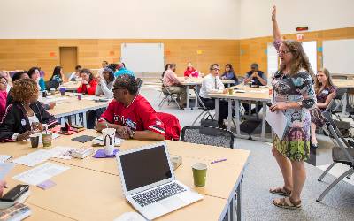 Professional development facilitator raising her hand to attendees